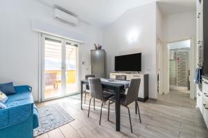 een woonkamer met een tafel, stoelen en een televisie bij Sole e Mare Buggerru - Appartamento in Buggerru
