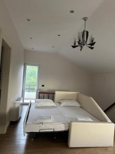 a white bedroom with a bed and a chandelier at Jon Private Vila  +12 photos