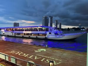 a cruise ship in the water with a city in the background at GO INN Asiatique BKK - โกอินน์ เอเชียทีค เจริญกรุง xPro in Godown