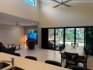 Una sala de estar con televisión, mesa y sillas. en Entire 4 bedroom home in Palm Cove, en Palm Cove