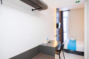 a room with a desk and a bed at Sans Vibes Hotel Damai Yogyakarta in Kejayan