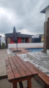 a wooden picnic table with an umbrella next to a pool at Vegas Guesthouse in Bushbuckridge
