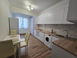 eine Küche mit weißen Schränken und einem Tisch und einer Spüle in der Unterkunft Красивая квартира на Телецентре in Chişinău