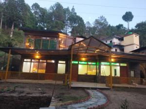 a house with a lot of windows on it at Pinaka Devbhumi Homestay in Mukteshwar