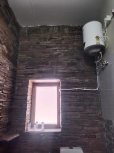 a window in a brick walled bathroom with a toilet at Pinaka Devbhumi Homestay in Mukteshwar