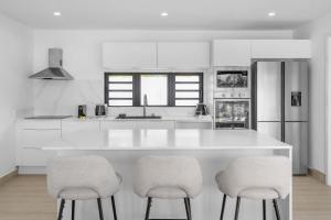 Bain BoeufVilla Rivalet - The perfect stay的厨房配有白色的柜台和2张凳子