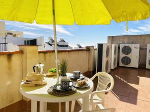 einen Tisch mit gelbem Regenschirm auf dem Balkon in der Unterkunft Apartamento San Miguel by At Home Costa del Sol in Nerja