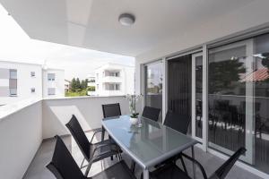a dining room with a glass table and chairs on a balcony at Villa Mel Mari luxury apartments with pool in Novalja