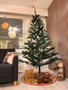 a christmas tree in a living room next to a couch at Warm Wooden Home in Rovaniemi in Rovaniemi