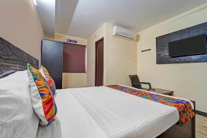 Un dormitorio con una cama y un televisor en la pared. en Via AB Top, en Coimbatore