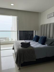 a bedroom with a bed with blue pillows and a window at Tu apartamento en la playa piso 10 in Cartagena de Indias