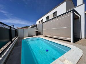 a swimming pool in front of a house with a garage at Casa Rural Cascadas del Hueznar in San Nicolás del Puerto