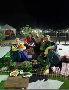 un groupe de personnes assises sur une couverture de pique-nique dans l'établissement Desert Surprise Resort, à Jaisalmer