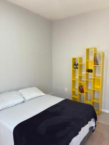 a bedroom with a bed and yellow shelves at Suíte - Centro de Itu in Itu