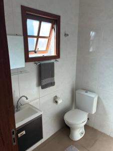 a bathroom with a toilet and a sink and a window at Suíte - Centro de Itu in Itu