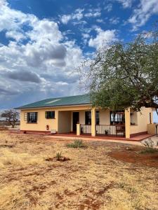 ein Gebäude in der Mitte eines Feldes in der Unterkunft Wild Amboseli Ndovu Cottage. in Amboseli-Nationalpark