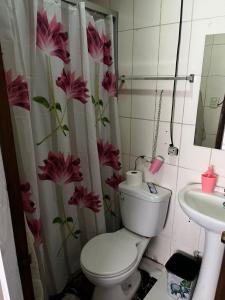 a bathroom with a toilet and a shower curtain with flowers at Hotel del valle san Miguel 530 in Melipilla