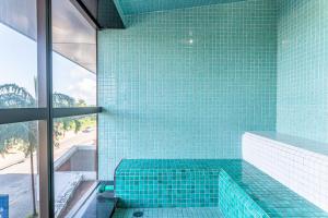 a bathroom with a blue tiled tub with a glass window at BHS Flat a beira mar 2203 in Recife
