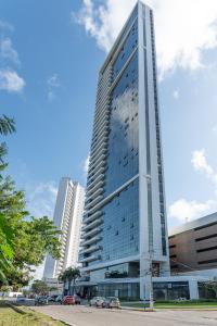 a tall glass building with cars parked in front of it at BHS Flat a beira mar 2203 in Recife