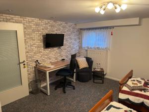 a room with a desk and a tv on a brick wall at Gästezimmer Neumann in Bad Münder am Deister