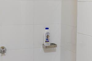 Una botella de producto de limpieza sobre una pared de azulejos blancos en el baño. en Hazel Studio with free WI-FI, en Nanyuki