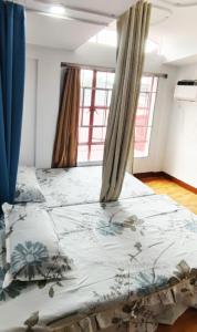 Cette chambre comprend un grand lit et des fenêtres. dans l'établissement Thai Nee Homestay, à Manille 5 autres photos