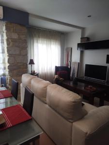 una sala de estar con un sofá y un televisor en Vivienda Turística Constitución Úbeda, en Úbeda
