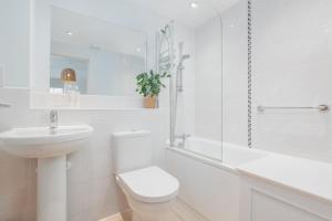 a white bathroom with a toilet and a sink at Saxon Mews in Wareham