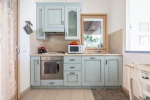 Una cocina con gabinetes azules y un microondas. en Villa Daisy, en Terra Mala