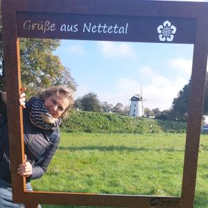 a woman in a sign with a windmill in the background at Pension Zur Mühle in Nettetal