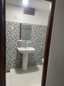a bathroom with a sink and a tiled wall at Penthouse Bandarawela in Bandarawela