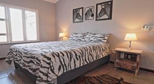 a zebra print bed in a bedroom with a table at Stripes & Sunsets Marloth Park in Marloth Park