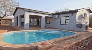 a swimming pool in front of a house at Stripes & Sunsets Marloth Park in Marloth Park
