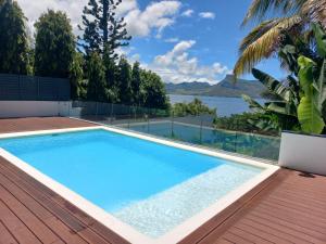a swimming pool on a deck with a view of the water at Villa moderne face a la mer in Mahébourg