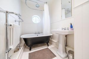 a bathroom with a black tub and a sink at Edinburgh House in Burnham Market +20 photos