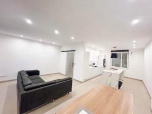 a living room with a black couch and a kitchen at Room in new a renovated house with modern furniture in Esch-sur-Alzette