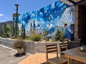 a mural on a wall with a table and chairs at Fathill Finca in Tamaide