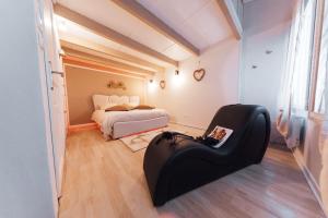 a bedroom with a bed and a black chair at Instants Précieux - Love Room in Arvert