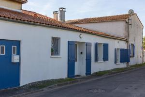 a white building with blue doors and a street at Instants Précieux - Love Room in Arvert