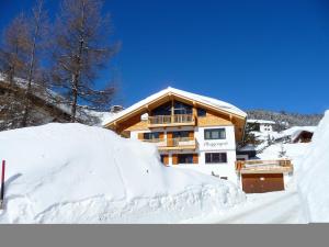a ski lodge with a pile of snow in front of it at Pension Muggengrat in Lech am Arlberg