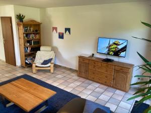 a living room with a flat screen tv on a wooden dresser at Ferienhaus Mehler - Heiligenhafen in Heiligenhafen +16 photos