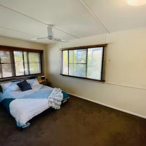 a bedroom with a bed and two windows at Relax & Unwind, 5BR Home with Pool Near CBD in Garbutt Station