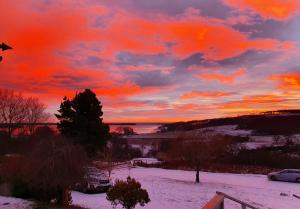 a sunset over a snowy field with a car at Strathview Lodge B&B in Dornoch