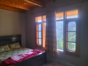 une chambre avec un lit et deux fenêtres dans l'établissement Ad cottage, à Nathia Gali