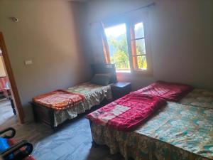 une chambre avec deux lits et une fenêtre dans l'établissement Ad cottage, à Nathia Gali