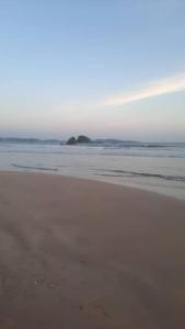 a sandy beach with an island in the ocean at ANGEL VILLA , Place with nature and care in Midigama West