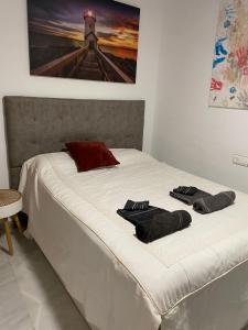 ein weißes Bett mit zwei Handtüchern darauf in der Unterkunft Encantador ático con chimenea y piscina en Almería in Retamar