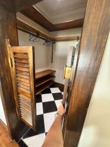 a person opening a door to a room with a checkered floor at Toni's Cottage in Graaff-Reinet