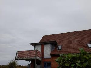 une maison en briques avec un toit rouge dans l'établissement Moderne Ferienwohnung mit Balkon in Strandnähe, à Friedrichskoog