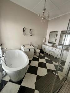 a bathroom with a large tub and a checkered floor at Toni's Cottage in Graaff-Reinet +27 photos